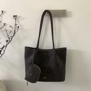 Detalle del bolso tote grande color carbón con logotipo dorado y monedero redondo a juego