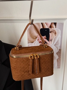 Brown woven texture mini box bag with top handle and gold chain strap in warm studio setting