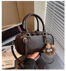 Detail of dark brown retro leather handbag with plush charm and adjustable strap