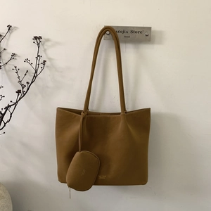 Primer plano de bolso tote de cuero marrón con mini estuche y detalle de logo dorado