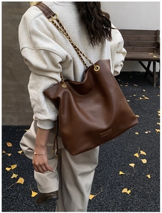 Deep brown leather bucket tote bag with chain strap shown in an autumn street setting