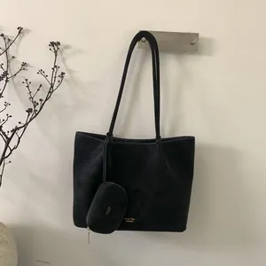 Detalle de bolso tote negro con costuras blancas y pequeño estuche con cremallera