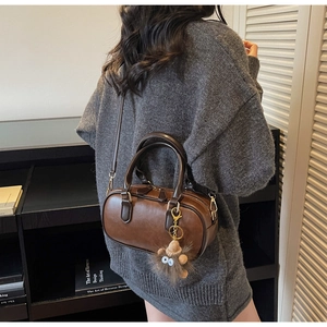 Brown vintage boston bag worn as a shoulder bag with a gray knitted dress on model