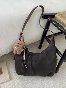 Grand sac cabas minimaliste en similicuir marron avec breloque ours sur une chaise en bois