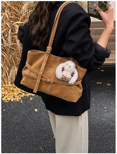 Detalle del bolso tote de ante marrón con hebilla decorativa y colgante de conejo suave