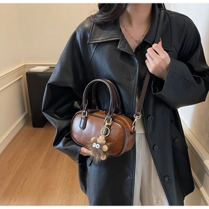 Braune Vintage-Bowlingtasche aus Leder mit Plüsch-Anhänger und stilvollem Freizeitoutfit