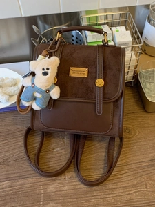Deep brown minimalist faux leather backpack with plush bear charm and metallic studs