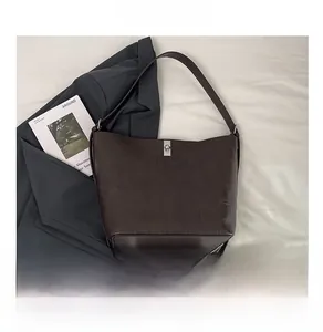Detail of dark brown embossed leather tote bag with silver clasp and phone for scale