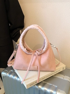 Pink suede tote bag with faux shearling trim and bow detail on a silver suitcase