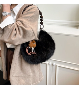 Black plush crescent bag featuring a unique wooden bead strap and cute fur ball charm