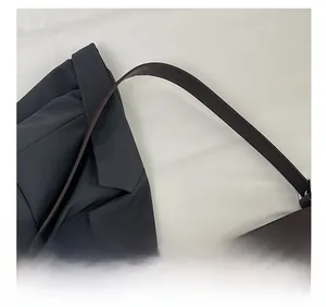 Macro view of dark brown embossed leather handbag with wide strap and silver metal buckle