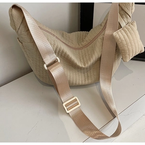Close-up of beige quilted nylon dumpling bag with adjustable strap and mini pouch