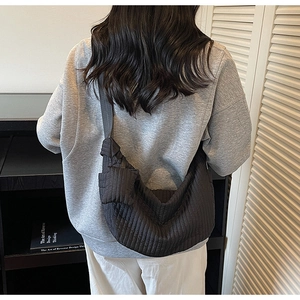 Close-up of quilted black half-moon crossbody bag with wavy striped nylon texture