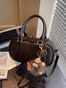 Vintage brown leather boston bag with furry charm and adjustable strap on office desk