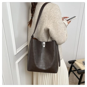 Close-up of vintage brown tote bag with silver buckle and vertical stitching detail