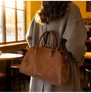 Detail view of large dark brown suede tote bag with adjustable strap in a café setting