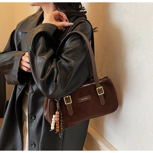 Detail of dark brown faux suede shoulder bag with beaded charm and adjustable strap