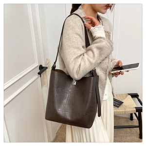 Detail of dark brown leather bucket bag with silver twist lock and smooth grain texture