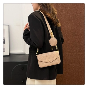 Detail of beige crossbody bag with embossed texture, gold hardware and mini pouch