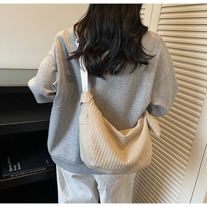 Beige quilted hobo bag with striped texture shown on a shoulder in a modern room
