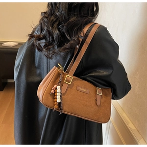 Detailed view of brown suede underarm bag with vintage beads and metal brand tag