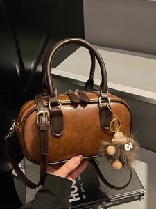 Vintage caramel cylinder handbag with dark brown handles and cute plush monster charm