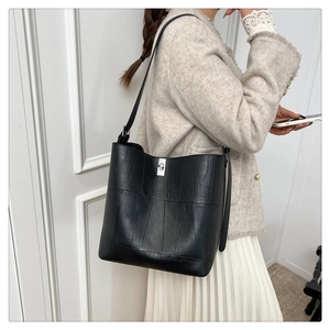 Detail view of black faux leather bucket bag with vertical stitching and silver twist lock