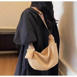Detail of light tan pleated dumpling bag showing vertical texture and crescent shape