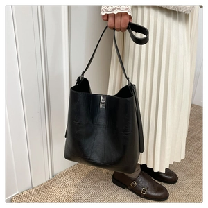 Close-up of black leather bucket bag with silver metal buckle and vertical stitching