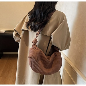 Detail view of brown quilted hobo bag with adjustable shoulder strap on a model