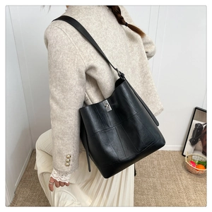 Detail of black leather bucket bag featuring a silver twist lock and vertical stitching