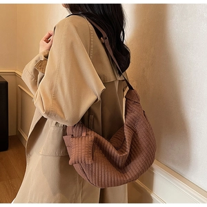 Detail of coffee brown pleated hobo bag showing quilted texture on a trench coat model