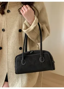 Détail d'un sac bandoulière noir en suède avec coutures blanches contrastées sur tissu
