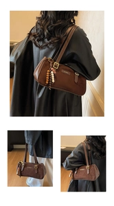 Detail of brown faux suede baguette bag featuring a retro beaded charm and brand plaque
