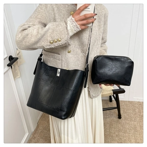 Detail of black leather bucket bag set with silver metal twist lock on an elegant outfit