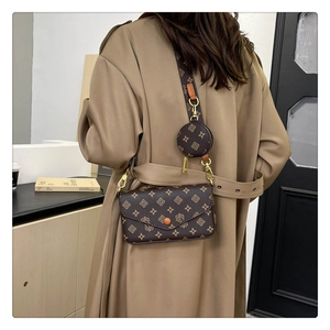 Detail of dark brown patterned baguette bag set with wide shoulder strap on beige trench coat