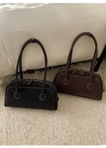 Gros plan sur des sacs en daim noir et marron avec coutures blanches et fermetures