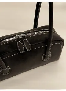 Détail du sac en cuir noir mat avec coutures blanches contrastées et doubles zips argentés