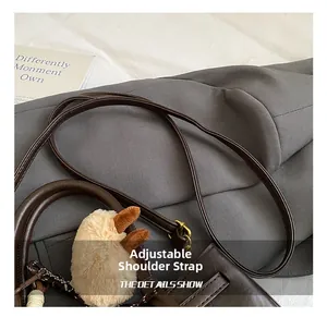 Detail of dark brown leather handbag with adjustable strap and plush rabbit ear charm