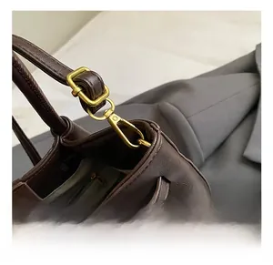 Detail shot of vintage gold hardware and zipper on dark brown leather bucket handbag