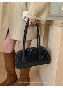 Détail du sac baguette en daim noir avec surpiqûres blanches et double poignée élégante