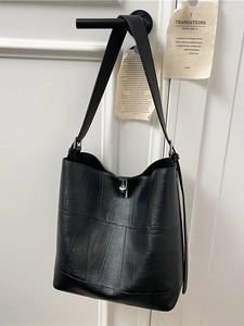 Minimalist black leather bucket bag with stitched panel design and silver twist lock