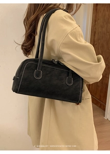 Détail du sac baguette vintage en daim noir avec surpiqûres blanches contrastées et anse