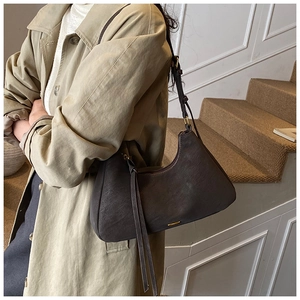 Detail of dark brown retro crescent shoulder bag with tassel and gold metal buckle