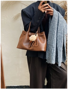 Detail of vintage brown leather handbag with plush charm and side profile on a model