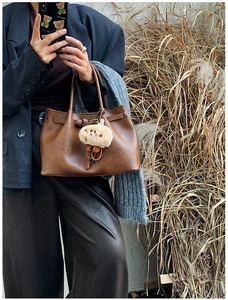 Brown faux leather handbag featuring a plush bear charm shown in a chic mirror selfie style
