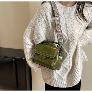 Detail of vintage dark green crossbody bag with ethnic patterned wide woven strap