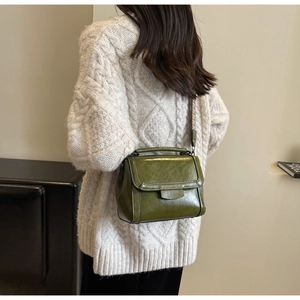Detail of an olive green oil wax leather crossbody bag with a wide jacquard strap
