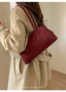 Détail du sac rouge en daim avec surpiqûres contrastées sur manteau en laine beige