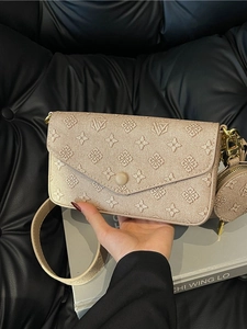 Champagne gold monogram baguette bag with wide strap and round coin purse on black sofa